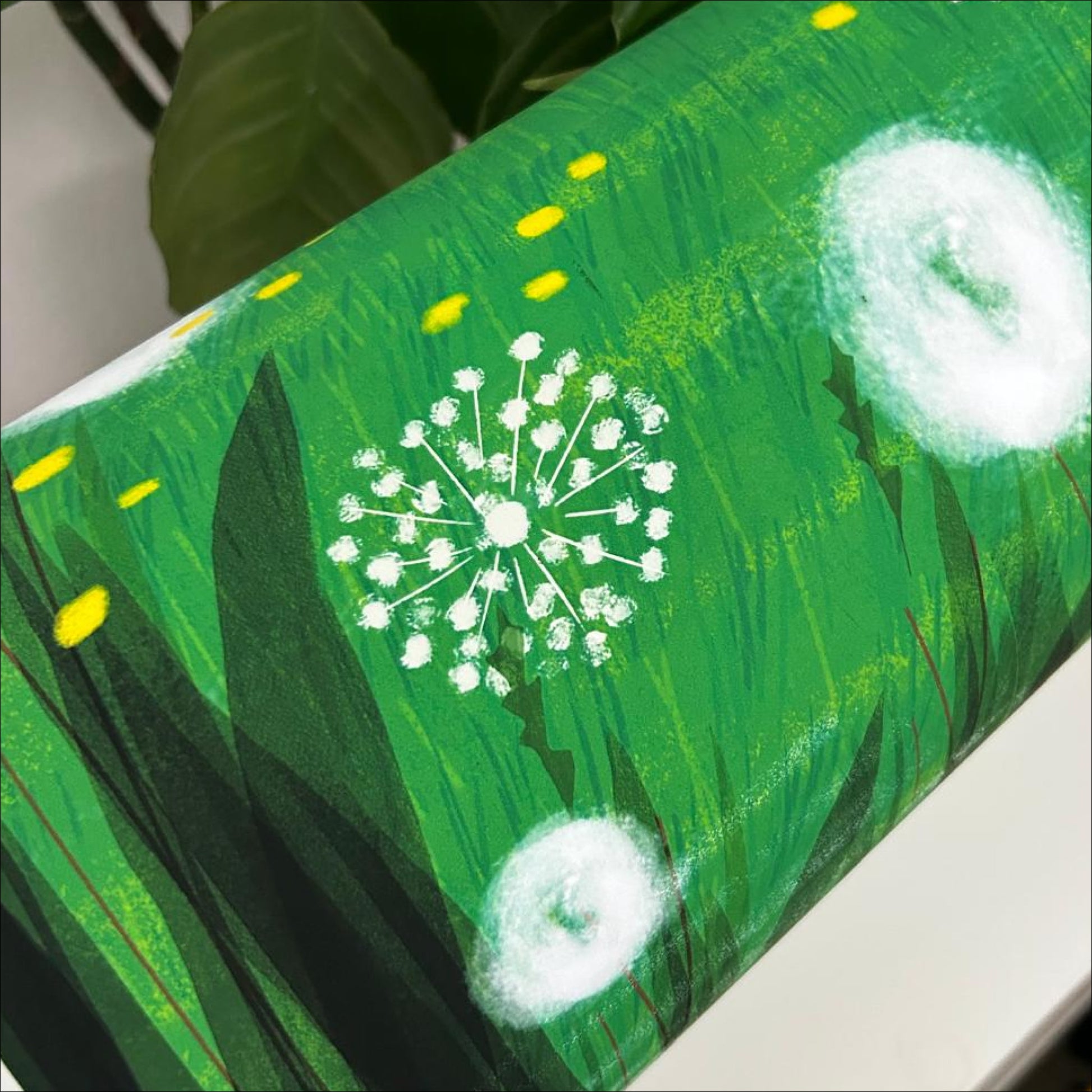 Close-up of Resting Field art print on a table showing dandelion and yellow wildflower detail, OAM Studio