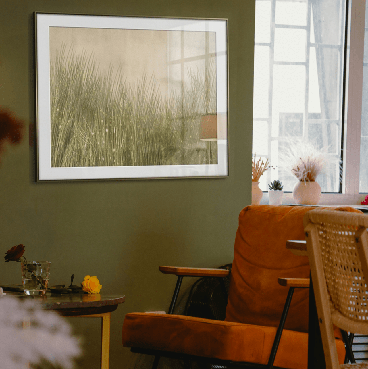 Living room with a framed picture on the wall, brown armchair, and wicker chair. created by oam studio