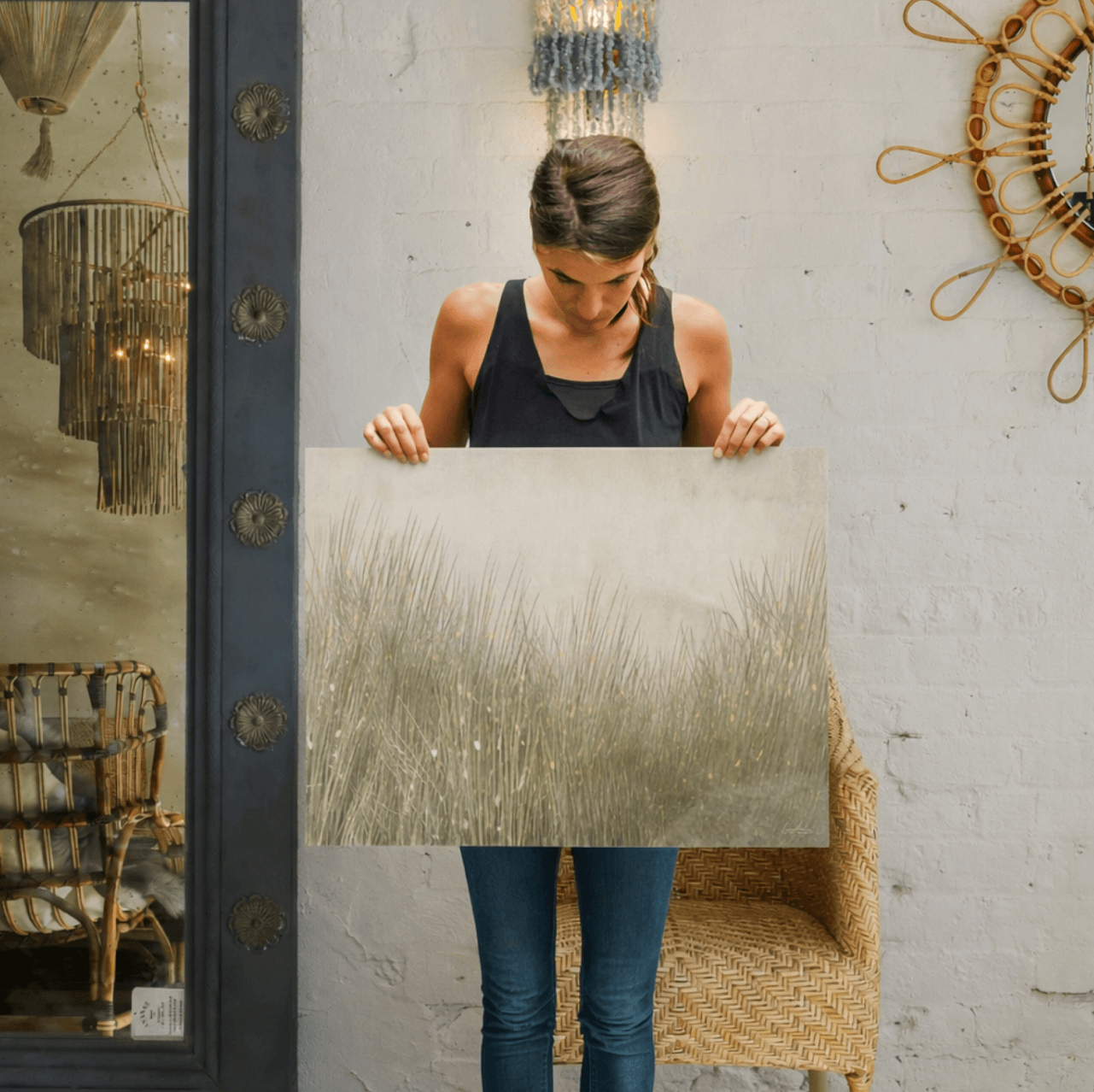 Woman holding a rectangular metallic object in an indoor setting with decorative elements created by oam studio